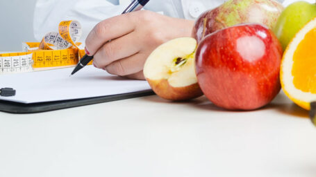 Nutritionist desk with healthy fruit, vegetables and a measuring tape