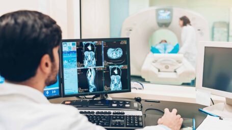 A healthcare professional looking at a monitor with a patient's MRI scan results