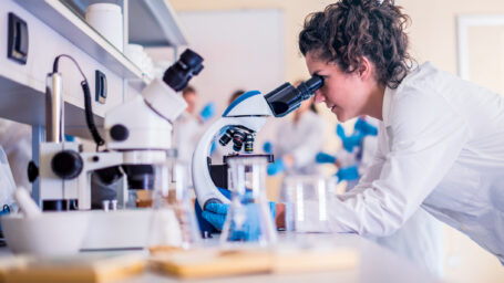 Scientist in lab doing research and using lab machines, test tubes, microscope and every laboratory equipment