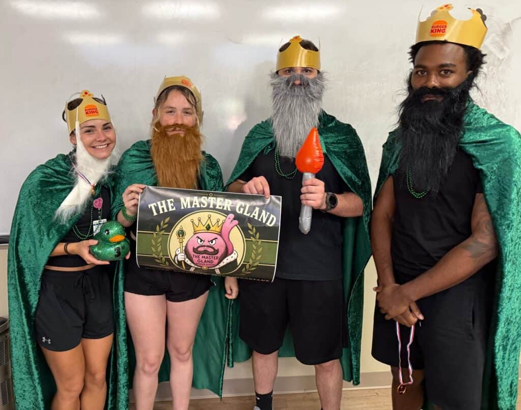 Four PA students dressed as kings and holding a sign that says The Master Gland