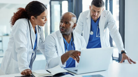 A diverse group of physician assistants discussing something on a laptop