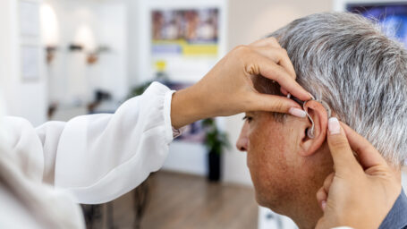 Female doctor fitting a male patient with a hearing aid